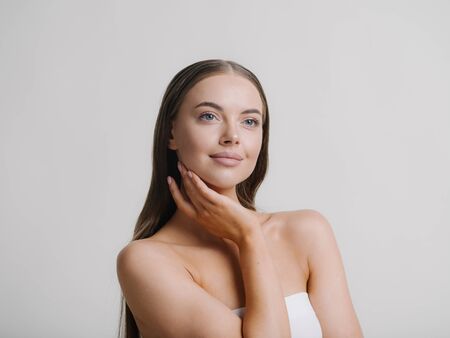 Natural beauty woman with heands touching face long brunette hair beautiful neck and shoulders Studio shot.の写真素材