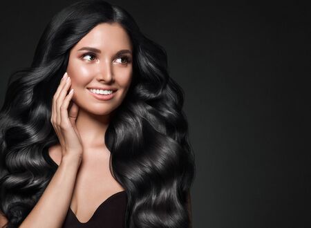 Black hair woman long curly beauty cosmetic concept over black background. Studio shot.の写真素材