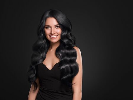 Black hair woman long curly beauty cosmetic concept over black background. Studio shot.の写真素材