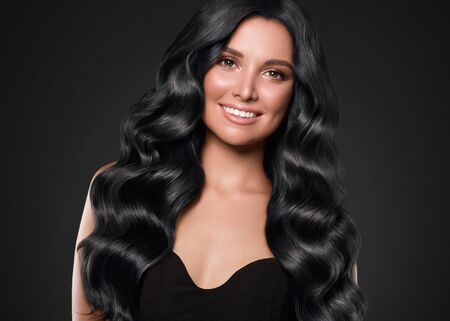 Black hair woman long curly beauty cosmetic concept over black background. Studio shot.の写真素材