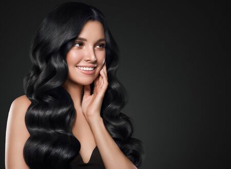 Black hair woman long curly beauty cosmetic concept over black background. Studio shot.の写真素材