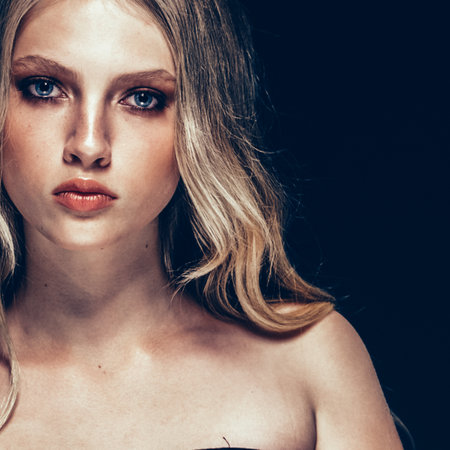 Beautiful Blonde Woman Beauty Model Girl with perfect makeup and hairstyle over black background.の写真素材