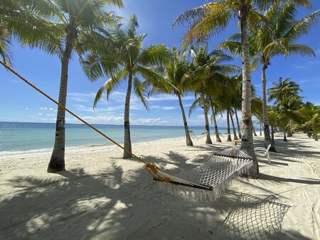 Relaxing hammock in a palm forest close-up.Beautiful white sandy beach.Boats on the background of sea.Ð¡oncept of travelの写真素材