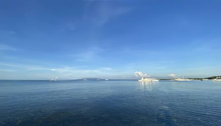 Beautiful monochrome panorama of blue sky and calm sea. A ship and boats drift in the water on the...