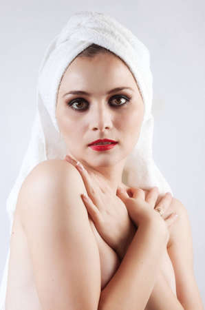 Young beautiful girl in the sauna towel looks directly at the camera. The background is white.の写真素材