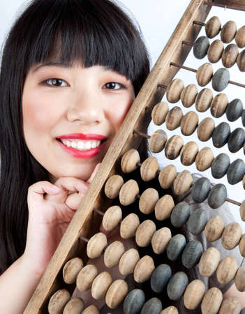 The young Chinese girl holds a wooden abacus in the hands.の写真素材