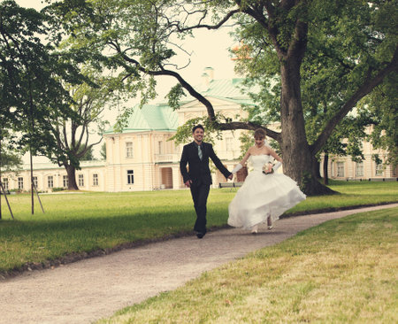  groom and the bride run on a path in palace parkの写真素材