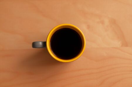Dark coffee cup on wooden background top viewの写真素材