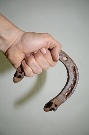 The old horseshoe in his hand working on the background of a gray wall の写真素材