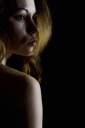 Portrait of a beautiful girl in a backlit against a dark background.の写真素材