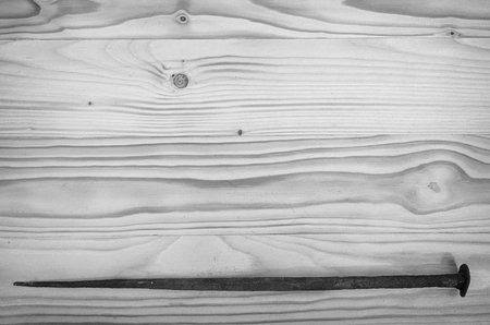 An old forged nail on a wooden table in black and white.の写真素材