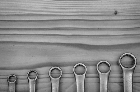Wrenches on a wooden table in black and white.