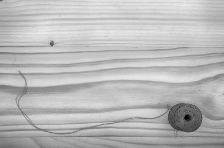 The old reel of thread and a needle on a wooden table in black and white.の写真素材