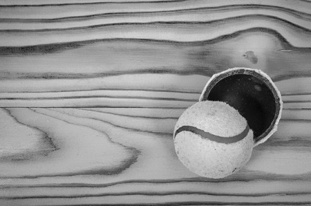 Torn tennis ball on a wooden table in black and white.の写真素材