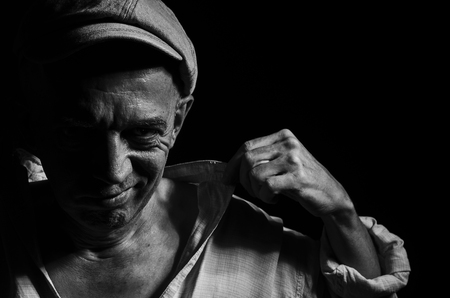 Portrait of an elderly man in a cap on a dark background .の写真素材