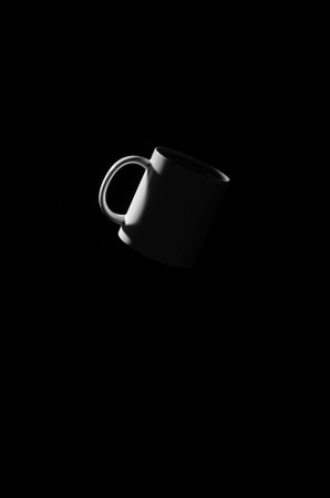 White cup floating in space on a black background.の写真素材