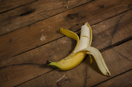 A bitten banana on a dirty wooden table.の写真素材