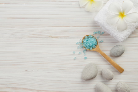 beautiful composition of spa treatment on wooden background. salt, spoon, stone, towel and flowersの写真素材