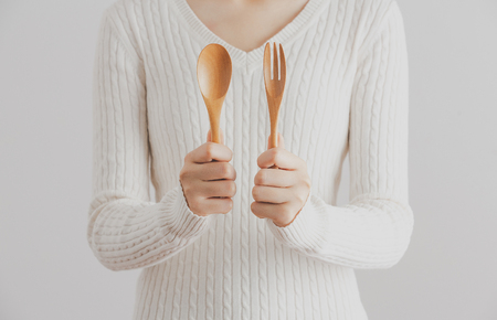 Woman wear sweater holding spoon and fork on white background, healthy woman, healthy food and lifestyle concept.の写真素材