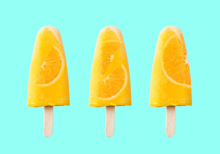 Tasty and refreshing orange popsicles on blue background.の写真素材