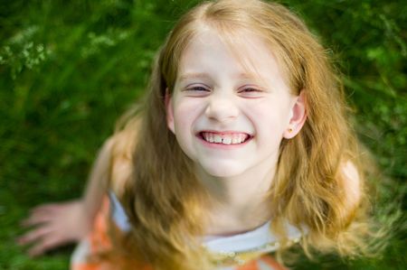 Smiling little girl outside in green grass 