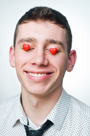 Portrait of a smiling man with heart-shaped candies over his eyes の写真素材