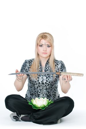 Woman sitting in lotus pose with katana, isolated on white background の写真素材