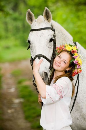 Smiling girl in floral wreath with horse  の写真素材