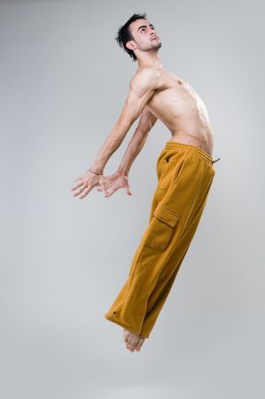 Young dancer jumping, studio shot over gray background  の写真素材