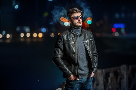 Stylish young man in the lights of the city at nightの写真素材