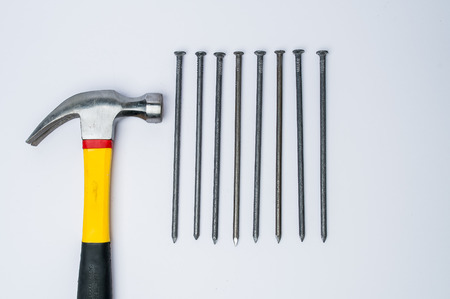 Hammer with few hammered and bended nails isolated on white background