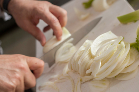 Chef cutting onions on white boardの写真素材