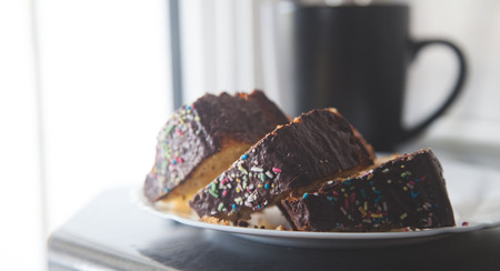 Three slices of cake with black cup in background shot with daylight