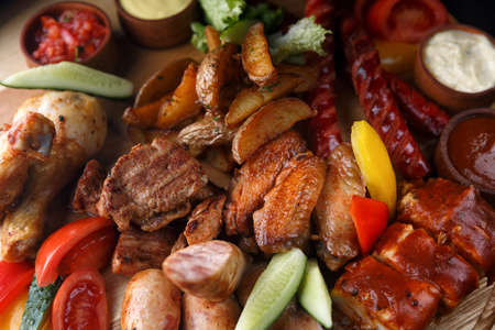 Assorted meat and sausages on a wooden boardの写真素材