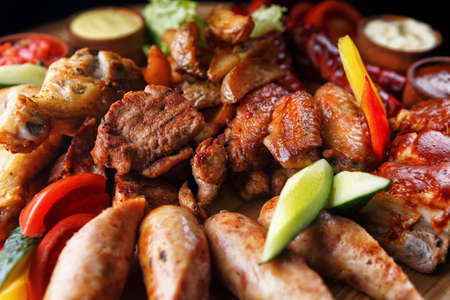 Assorted meat and sausages on a wooden boardの写真素材