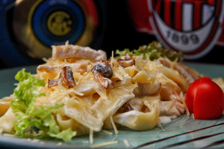 Pasta with meat and mushrooms, on a blue plate, on a black backgroundの写真素材