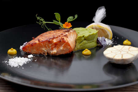 Piece of the fried salmon on a black dish with a lemon. steak. Filetの写真素材
