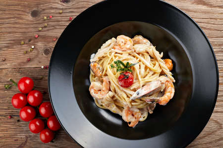 Spagetti with shrimp on a black plate (Fettuccine)の写真素材