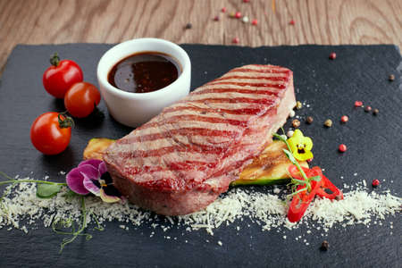 Meat steak with a sauce, on a black stoneの写真素材