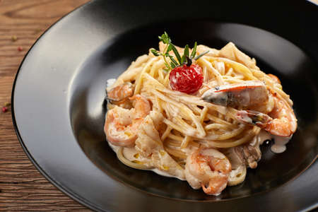 Spagetti with shrimp on a black plate (Fettuccine)の写真素材