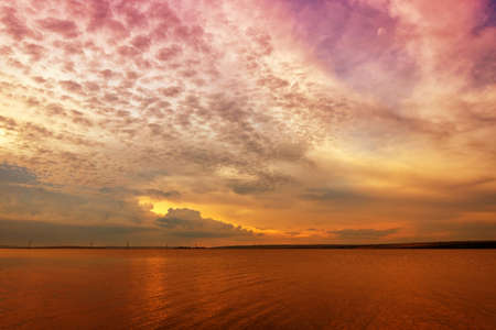 Beautiful sunset on the lake with clouds and reflections on the waterの写真素材