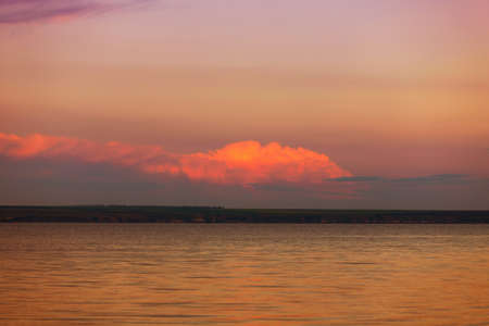 Beautiful sunset on the lake with clouds and reflections on the waterの写真素材