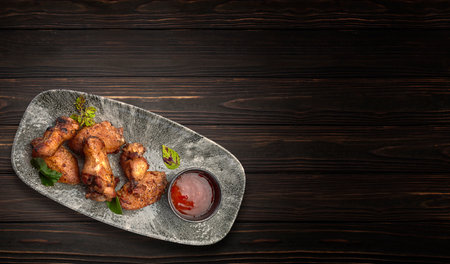 BBQ chicken legs with spicy sauce. Horizontal frame, on a dark wooden backgroundの写真素材
