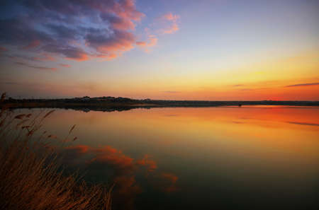 Beautiful sunset over the lake with beautiful evening clouds and water reflectionの写真素材