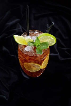 Alcoholic cocktail, Long island ice tee, on black velvet, on a black background with lime and mintの写真素材