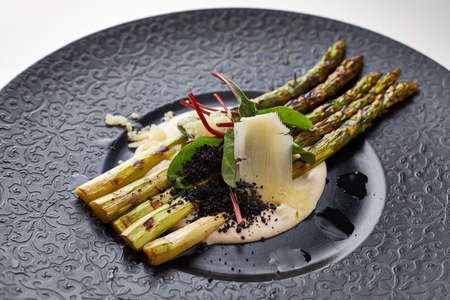Asparagus with Parmesan on a black plateの写真素材