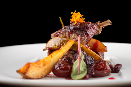 Duck leg with pear on a white plateの写真素材