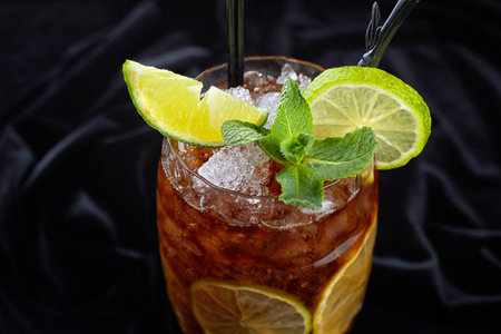 Alcoholic cocktail, Long island ice tee, on black velvet, on a black background with lime and mintの写真素材