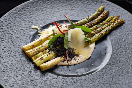 Asparagus with Parmesan on a black plateの写真素材
