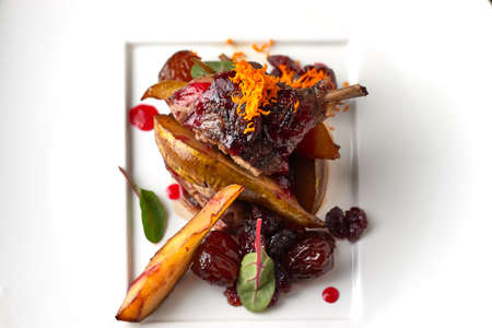 Duck leg with pear on a white plateの写真素材